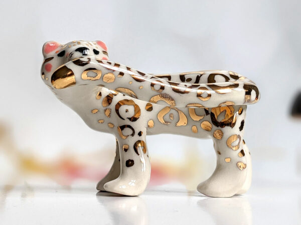 snow leopard munching tail porcelain figurine