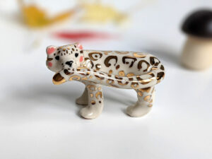 snow leopard munching tail porcelain figurine