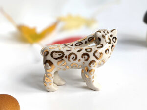snow leopard munching tail porcelain figurine