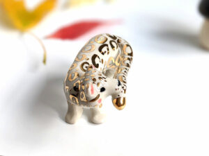 snow leopard munching tail porcelain figurine