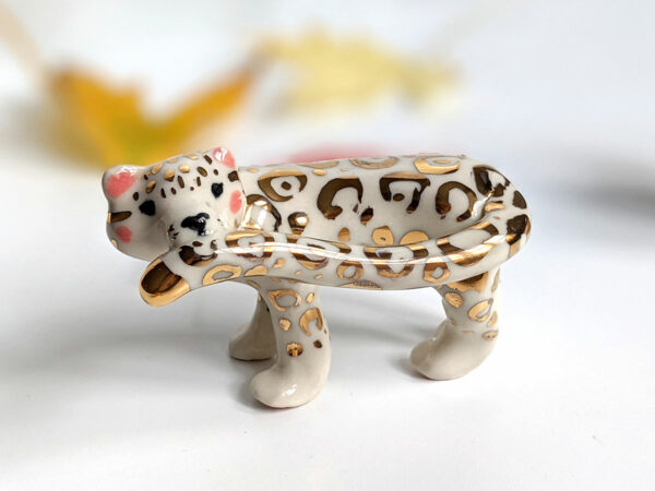 snow leopard munching tail porcelain figurine