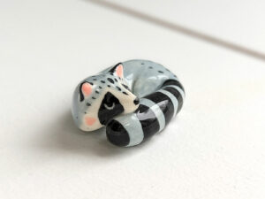 sleepy raccoon porcelain figurine