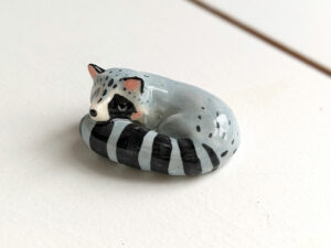 sleepy raccoon porcelain figurine