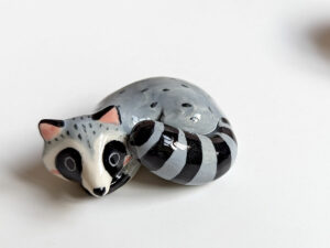 sleepy raccoon porcelain figurine