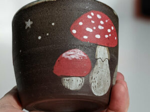 black clay cup with cute hedgehog and mushroom