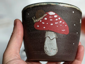 black clay cup with cute hedgehog and mushroom