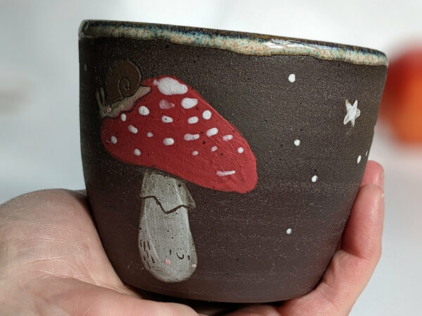 black clay cup with cute hedgehog and mushroom