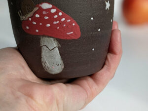 black clay cup with cute hedgehog and mushroom