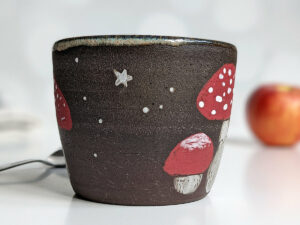 black clay cup with cute hedgehog and mushroom