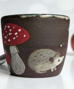 black clay cup with cute hedgehog and mushroom