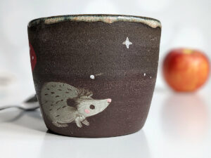 black clay cup with cute hedgehog and mushroom