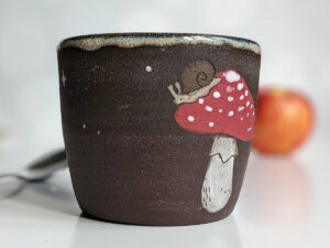 black clay cup with cute hedgehog and mushroom