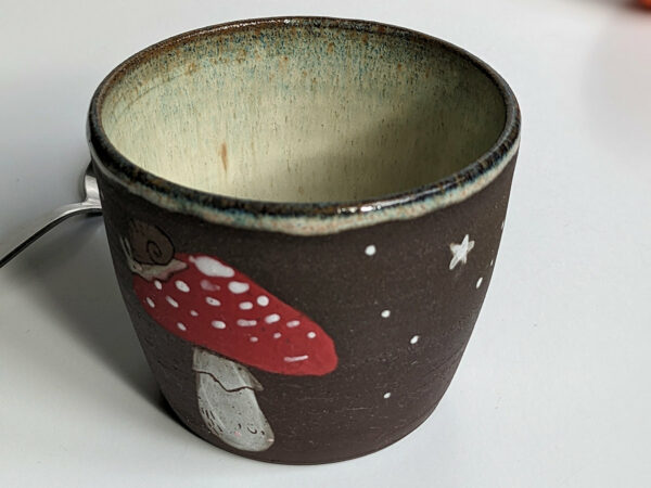 black clay cup with cute hedgehog and mushroom